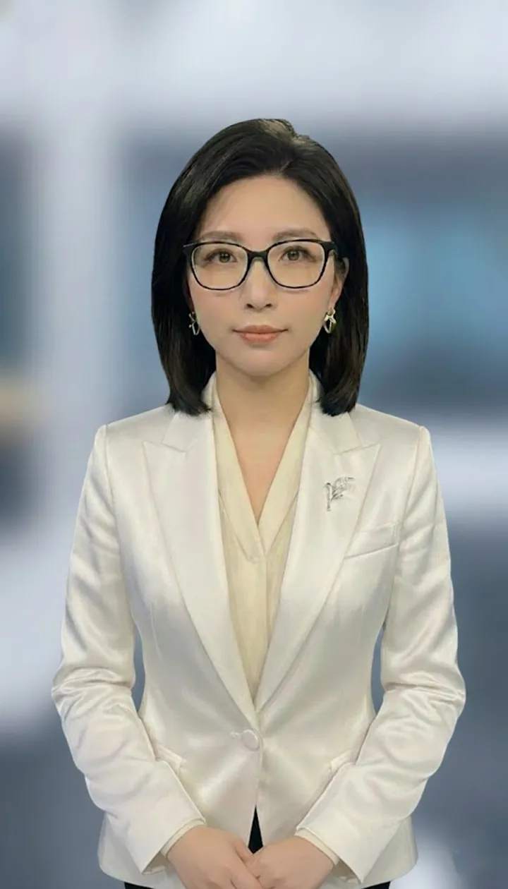 戴黑框眼镜的中青年女性穿白色西装，站在简洁的职场背景前